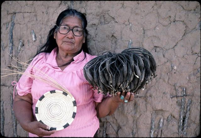 Beatrice Manuel holds a basket that she made and a bundle of devil's claw, called a hat_image #7.jpg
